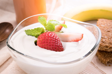 Plain yogurt with fresh strawberry on top in bowl on the table