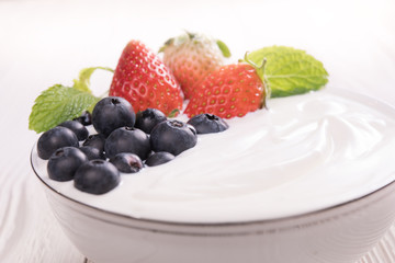 Plain yogurt with fresh berry fruits on top in bowl on the table