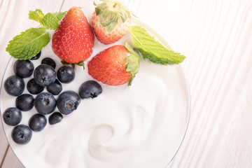 Plain yogurt with fresh berry fruits on top in bowl on the table