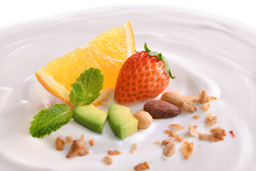 Plain yogurt with fresh fruits and granola on top isolated on white background