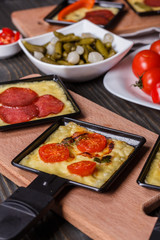 young woman is preparing a traditional Swiss cheese raclette
