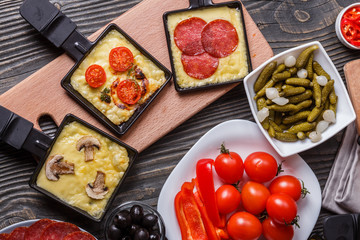 young woman is preparing a traditional Swiss cheese raclette