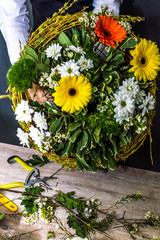 Young woman florist collects a bouquet of flowers in a flower shop. On the table are the tools for the florist. Close-up. Vertical photo