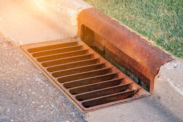 rusty sewer by footpath with sunlight effect