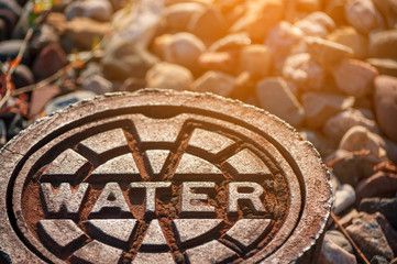 rusty water supply lid on ground with reflection and sunlight effect