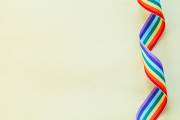 LGBT rainbow ribbon isolated on yellow background, copy space, top view, flat layout