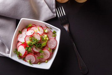Radish salad in a white bowl on a dark background