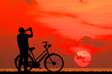 Fototapeta premium Silhouette man and bike relaxing on blurry sky background.