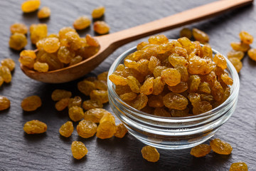 golden raisins on a dark stone background