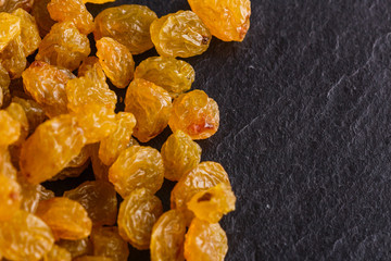 golden raisins on a dark stone background