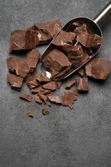 Dark Chocolate chunks in metal scoop on dark concrete background