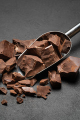 Dark Chocolate chunks in metal scoop on dark concrete background