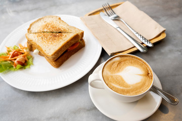 Hot latte coffee and sandwiches on the marble table