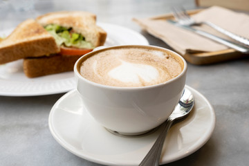 Hot latte coffee and sandwiches on the marble table
