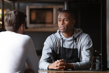African chef talking with caucasian male vacancy candidate in restaurant