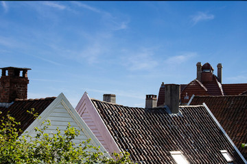 Close up detail of town house rooftops with chimneys against blue sky.