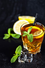 Traditional iced tea with lemon, mint leaves and ice cubes in glass.