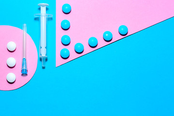 Medical stuff and pills minimalistic flat lay with copy space on a paper background of blue and pink.