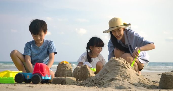 Family On Summer Vacation playing on the beach building sand castle together. Slow motion. Family, Holiday and Travel concept.