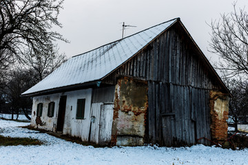 old colorful abandoned barn at a snowy winter day in an suburbal village