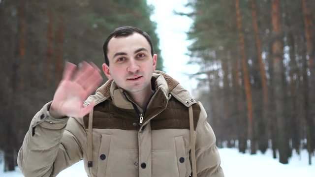 Outdoor portrait of handsome man in jacket is greeting at camera.