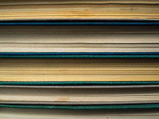 The outdated books put at each other. The turned yellow dusty pages of books. Color covers of books