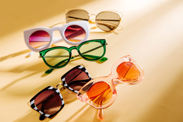Set of Stylish sunglasses with bright sunlight on yellow background. Flat lay, top view. Summer...