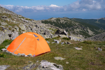 Camping in the mountains. Orange touristic tent.