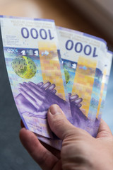 hand holding a stack of 1000 Swiss francs banknotes