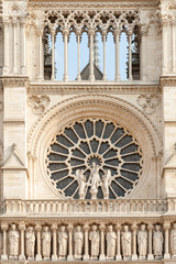 Fototapeta na wymiar Close up of Notre Dame de Paris cathedral facade with rose window and row of stone statues in Paris, France