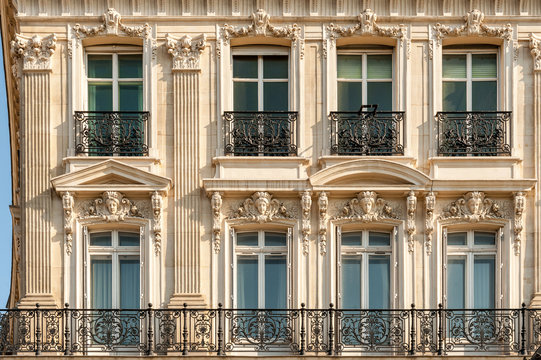 Facade of one of the beautiful buildings along Champs Elysees avenue with typical wrought iron fences and modeling, Paris, France