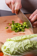 young woman slicing herbs in a gray apron
