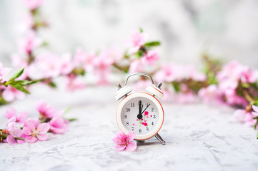 Spring blossom concept. Miniature clock, flowering tree close-up and copy space. Pink natural texture of natural flowering tree.