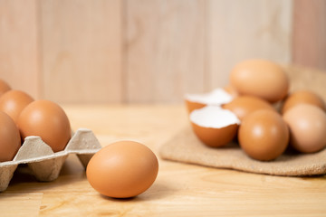 Brown eggs in carton box. Broken egg in background