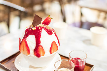 Korean shaved ice dessert with sweet strawberry toppings, Strawberry Bingsu. (Frozen milk spinning to snow flake and topped with fruits and syrup) 