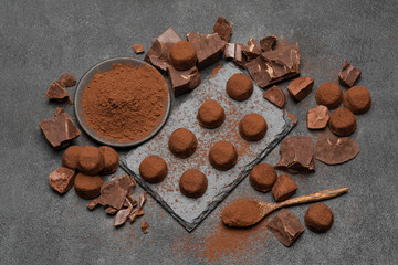 classic chocolate truffles and pieces of chocolate on dark concrete background