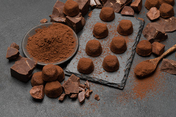 classic chocolate truffles and pieces of chocolate on dark concrete background