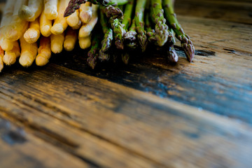 fresh organic green and white asparagus on an old rustic brown wooden table