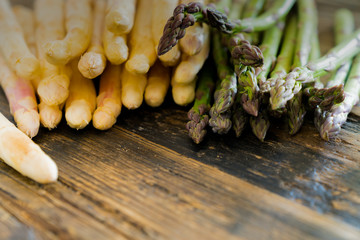 fresh organic green and white asparagus on an old rustic brown wooden table