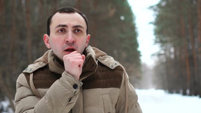 portrait of a frozen, cold man who coughing outdoors in the winter