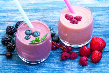 Raspberry, strawberry, blueberry smoothie on blue wooden background. milkshake with fresh berries. fruit smoothie with ingredients. well being and weight loss concept. top view