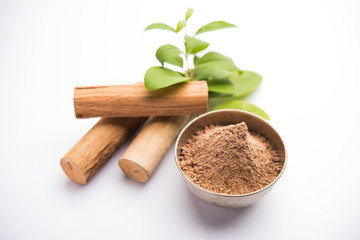 Chandan or sandalwood powder with sticks and green leaves