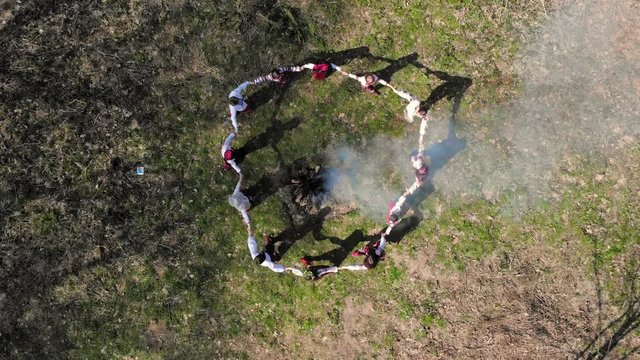 Aerail view on top. Group of children dancing around the fire holding hands