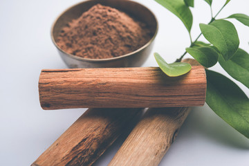 Chandan or sandalwood powder with sticks and green leaves