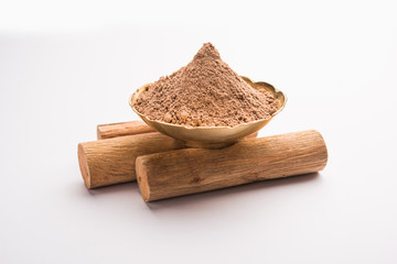 Chandan or sandalwood powder with sticks and green leaves