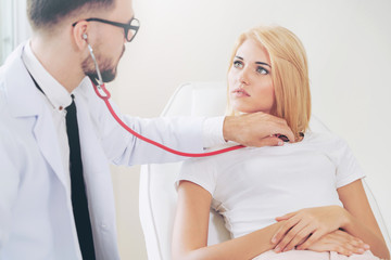 Male doctor is talking and examining female patient in hospital office. Healthcare and medical...