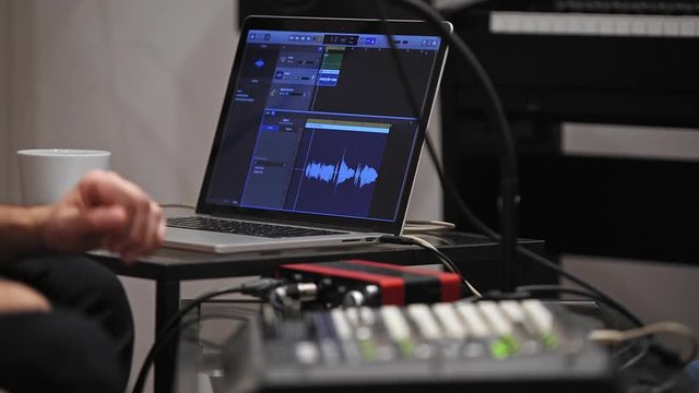Close up of musician playing midi keyboard in home music studio.