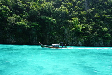 Longtail boat on tropical island in thailand crystal clear water