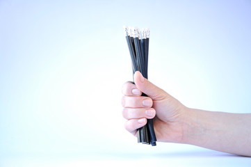 many black pencils in hand on white background