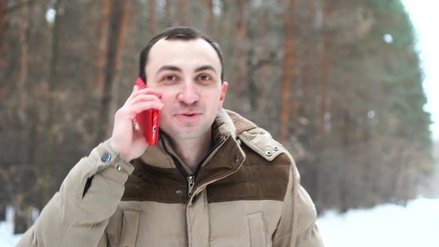Portrait of young man talking on phone in winter forest